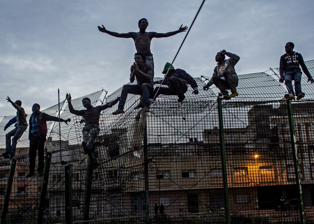 Sergi CÃ¡mara, The Wall of Europe, Spain, 2014. Young Africans trying to climb the double fence that separates Africa from Europe, near Beni Enza on the border of Spanish exclave Melilla in MarchÂ 2014. After spending several hours on top of the fence the Spanish security forces forced them back to Morocco. Courtesy of the artist.